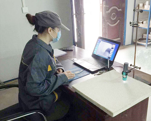 Technician inspecting the pore structure and surface quality of a ceramic foam filter using a digital microscope